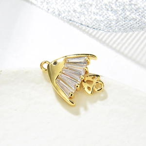 Macro shot of gold-plated fish pendant with colorful zircon stones and dual connectors