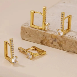 Détail macro de boucles d'oreilles créoles carrées dorées avec oxydes de zirconium