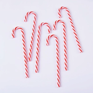 Detail of six red and white striped acrylic candy cane ornaments for Christmas tree decor