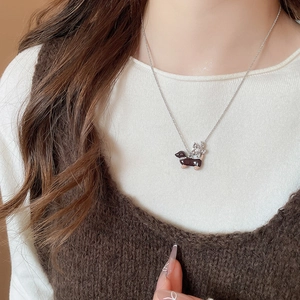 Détail du collier pendentif teckel avec fleur argentée et perle porté par femme