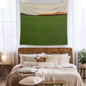 Detail of bohemian tapestry with abstract green hills above a wooden bed headboard
