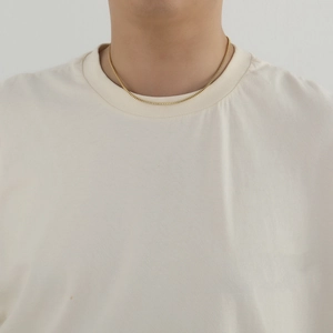 Detail of 2mm gold stainless steel box chain necklace worn on a model's neck