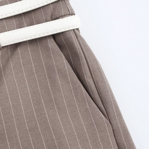 Close-up of brown pinstripe trousers featuring double white faux crocodile leather belts