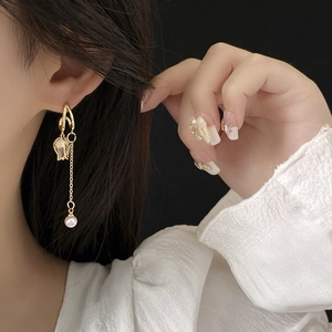 Détail des boucles d'oreilles tulipes dorées avec cristaux et perle blanche pendante