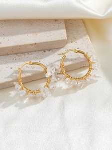 Detailed macro view of bohemian gold hoop earrings featuring natural clear crystal stones
