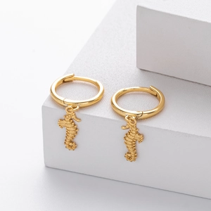 Detailed view of golden seahorse hoop earrings on a white plaster display stand