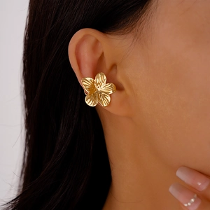 Detailed close-up of a golden flower ear cuff with textured petals worn by a model