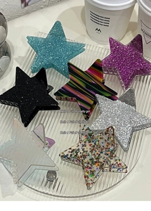 Detail showing seven star-shaped hair claws in glitter and pearlescent finishes