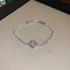 Close-up of silver clover tennis bracelet with square zircon on textured display card