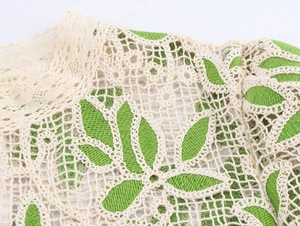 Vue macro détaillée du tissu vert avec motif complexe de dentelle blanche crochetée