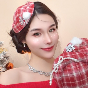 Detail of red plaid beret with snowflake brooch, pearl chain, and faux fur pompom