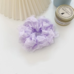 Detailed view of a purple pleated organza scrunchie displayed on a clean background
