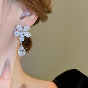 Close-up of a silver flower zircon earring with pear-shaped drops worn by a model