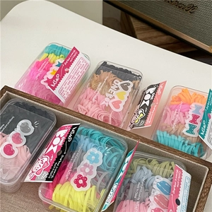 Detail of colorful elastic hair bands in clear boxes inside a brown storage basket