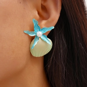 Macro detail of summer sea style starfish and shell earrings with white pearl accents