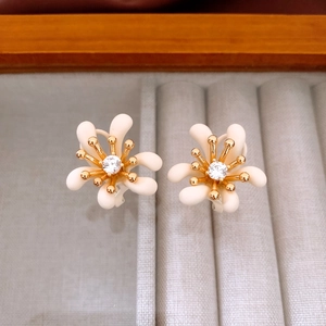 Dettaglio degli orecchini a lobo a fiore placcati in oro con zircone e petali bianco crema