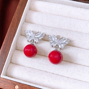 Detail of red butterfly drop earrings with white zircons on a rustic jewelry box