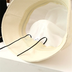 Close-up of cream tweed bucket hat interior with sweatband and adjustable drawstring