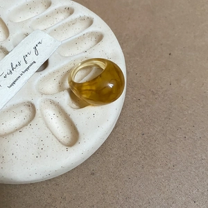 Detailed view of amber translucent resin ring on a textured tray with a gift card