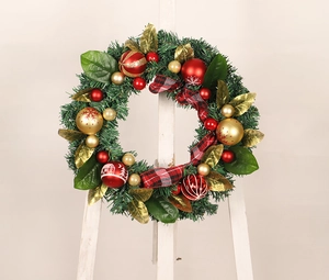 Detail of Christmas wreath with red and gold baubles, magnolia leaves, and plaid bow