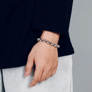 Detail view of a chunky silver stainless steel chain bracelet on a person's wrist