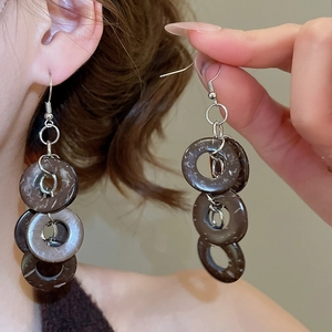 Detailed close-up of retro coconut shell tassel drop earrings on model with silver hooks