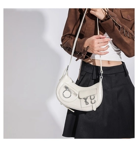 Détail du sac croissant blanc brillant avec anneau en métal argenté et finition vernie