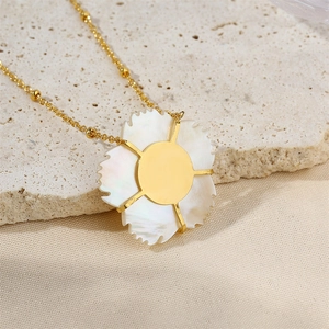 Detail of shell flower and pearl pendant on a gold beaded chain over silk fabric