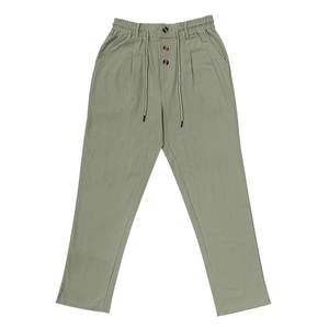 Detail of drawstring waist with decorative wood buttons on light green cotton linen trousers