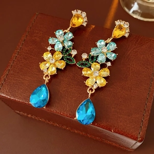 Macro shot of vintage floral drop earrings with yellow crystals and blue stone tassels