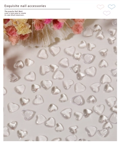 Macro shot of transparent heart-shaped resin nail art charms on cream background