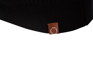 Close-up of black ribbed knit texture and premium brown decorative label on the hem