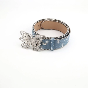Detail of denim belt with silver butterfly buckle, bead trim and distressed holes