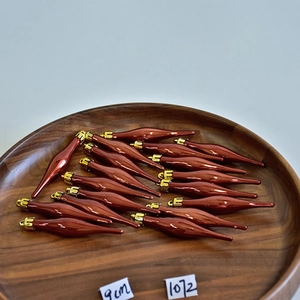 Detailed view of 9cm burgundy spindle-shaped Christmas ornaments on a wooden tray