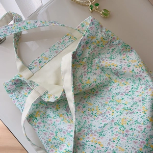Detail of floral canvas tote bag showing green tulip hair clip on a white surface