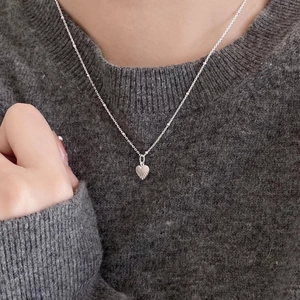 Elegant 925 sterling silver heart pendant necklace on a grey knit sweater background