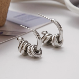 Detailed view of silver C-shaped twisted knot stud earrings in polished stainless steel