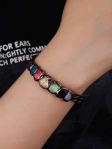 Detail of vintage copper cuff with multi-colored crystals worn on a female wrist