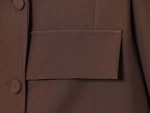 Détail de la texture du tissu marron foncé, poche à rabat et bouton recouvert assorti