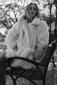 Close-up of belted faux fur coat with large lapels and plush texture in street style