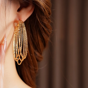Detail of layered gold multi-hoop earrings with textured brushed finish on model
