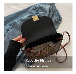 Interior view showing capacity of leopard print saddle bag with gold clasp and phone