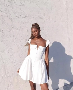 Detail view of white square neck mini dress with pleated hem and button front