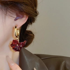 Close-up of model wearing vintage dark red flower drop earrings with gold metal hoops
