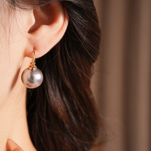 Close-up of a French vintage pearl earring worn by a model with a gold hook