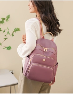 Dettaglio dello zaino viola con cerniere dorate e organizzazione a tasche multiple