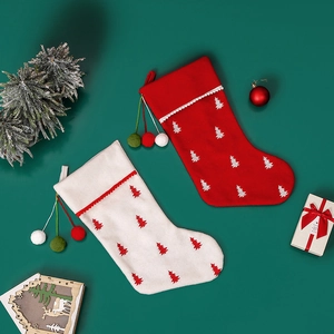 Pair of large Christmas stockings with tree patterns and pom poms on festive background