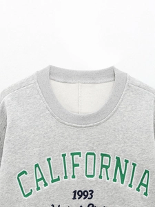 Détail d'un sweat gris avec broderie California 1993 et col rond en maille côtelée