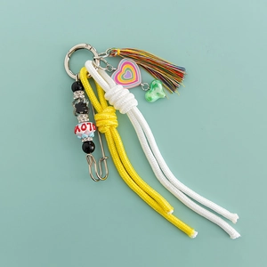 Close-up of pink heart macaron keychain with woven knots and colorful rhinestone tassels