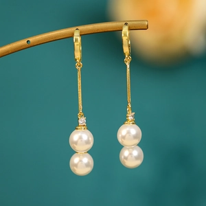 Detail of elegant gold hoop earrings with double white pearls and cubic zirconia